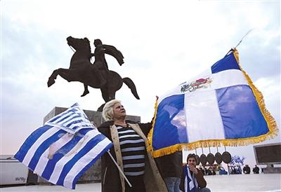 亚历山大/一名示威者在希腊北部城市的亚历山大大帝雕像前挥舞国旗，表示...