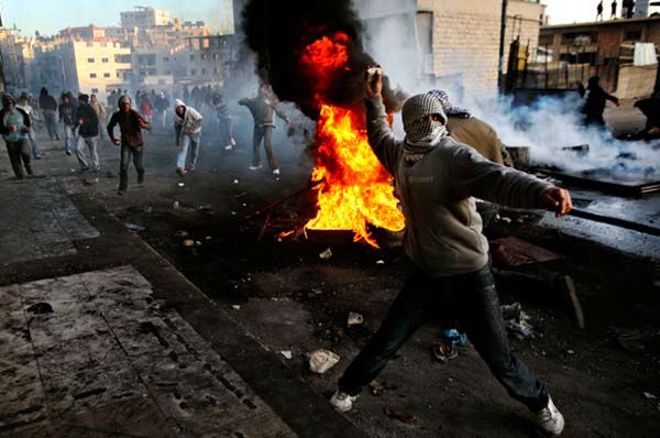 12月27日，在约旦河西岸城镇希伯伦，巴勒斯坦人向以色列士兵投掷石块。