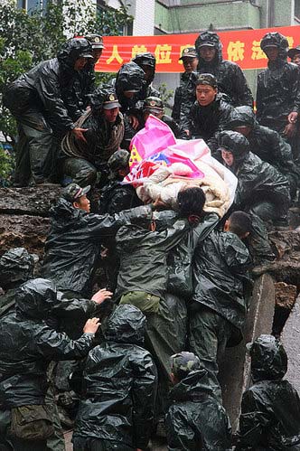 2008年5月13日，冒雨在废墟里抢救受伤难民的军人。