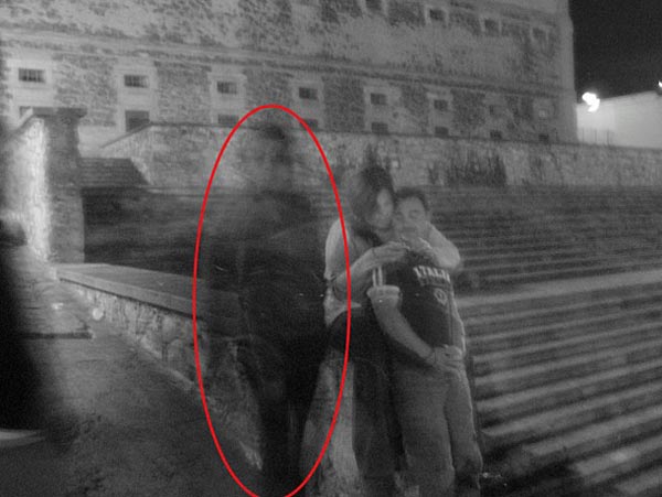 街头鬼影：一对夫妇坐在台阶上，一个奇怪的影子在旁边看着他们。怀疑者解释说，这个模糊的人影似乎是曝光时间过长造成的。可能是拍摄照片时，一位路人走过时造成的。