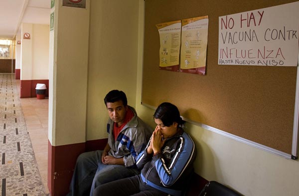 一对夫妻正在健康中心等待。他们头上的墙壁上写着：“现在没有疫苗能够防止病毒”