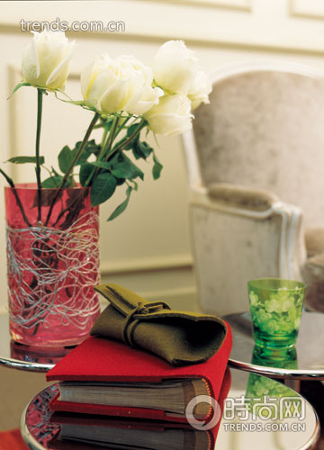 玫红色的玻璃花瓶上金属丝错落盘绕，将白玫瑰映衬得格外浪漫，绿色印花水杯更显得清新可人，红与绿搭配出动人的和谐。