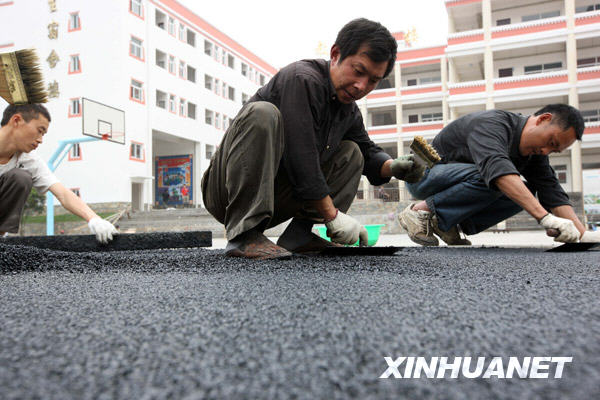 建筑工人在为四川省汶川县三江小学的操场铺设跑道