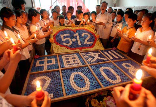 5月4日，卫云峰老人和前来参观的学生一起站在他用瓶盖制作的纪念“5·12”汶川大地震一周年纪念牌前，缅怀遇难同胞。