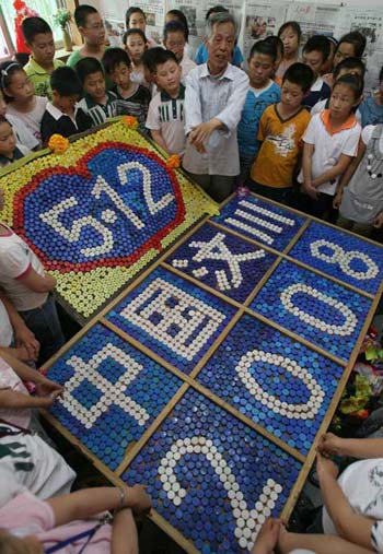 5月4日，卫云峰老人和前来参观的学生一起站在他用瓶盖制作的纪念“5·12”汶川大地震一周年纪念牌前，缅怀遇难同胞。