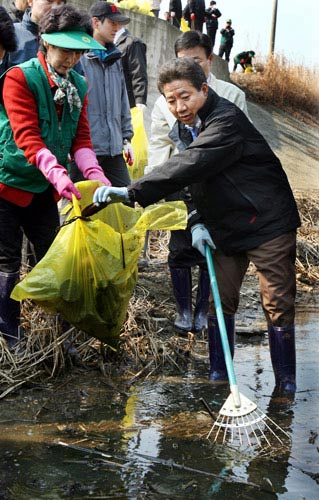 2008年3月6日，韩国前总统卢武铉卸任回乡后，作为一名环保志愿者，在其家乡庆尚省峰下村的溪水边和村民一起清理水中的垃圾。