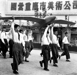 1959年，孩子们举着自己制作的航模飞机走过解放碑。


