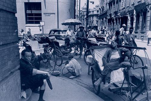 一位三轮车夫躺在车上酣睡，他正等着自己的乘客归来。（1948年5月，上海）

