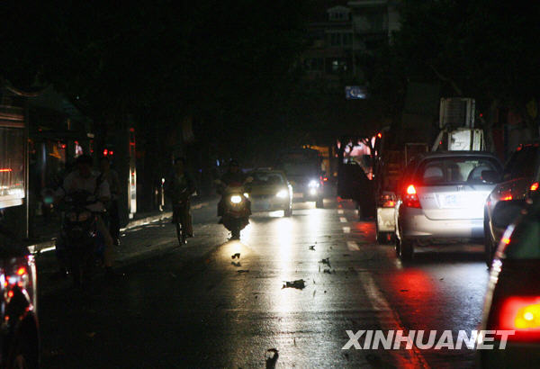 6月5日16时30分，汽车开着车灯行驶在光线昏暗的上海街道上。