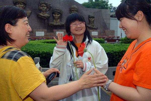 6月8日,，在北京回民學(xué)?？键c(diǎn)，一位家長（左一）給考生送上鮮花表示祝賀,。