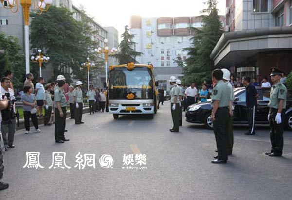 罗京儿子抱遗像上车。