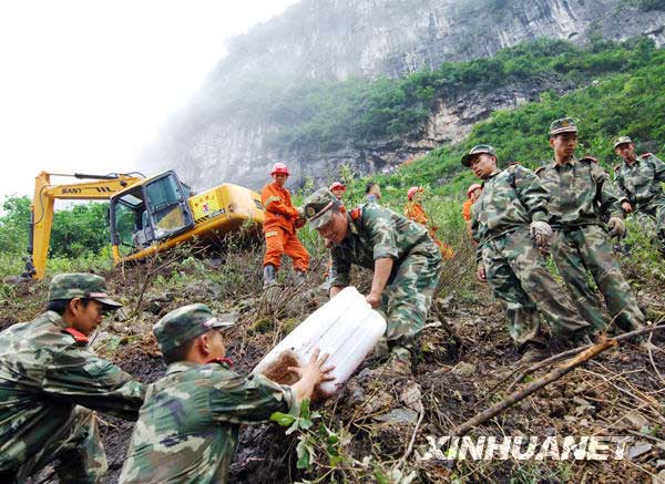  6月11日，救援人员在陡峭的山坡上为在海拔1020米作业的挖掘机运送油料。