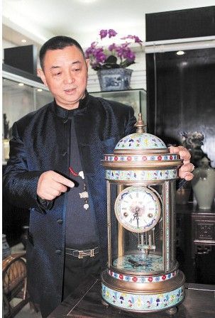 胡志坤向记者介绍1898年法国制造的珐琅彩西洋钟。肖亮 摄 。来源：长沙晚报
