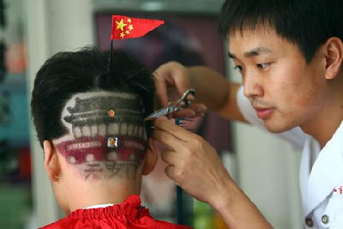 理发师正在为一个孩子剪天安门发型,头顶上还插了一面小国旗
