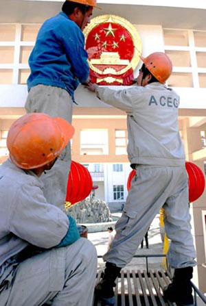 三名中国建筑工人将国徽挂在中国驻阿富汗大使馆的大门顶上